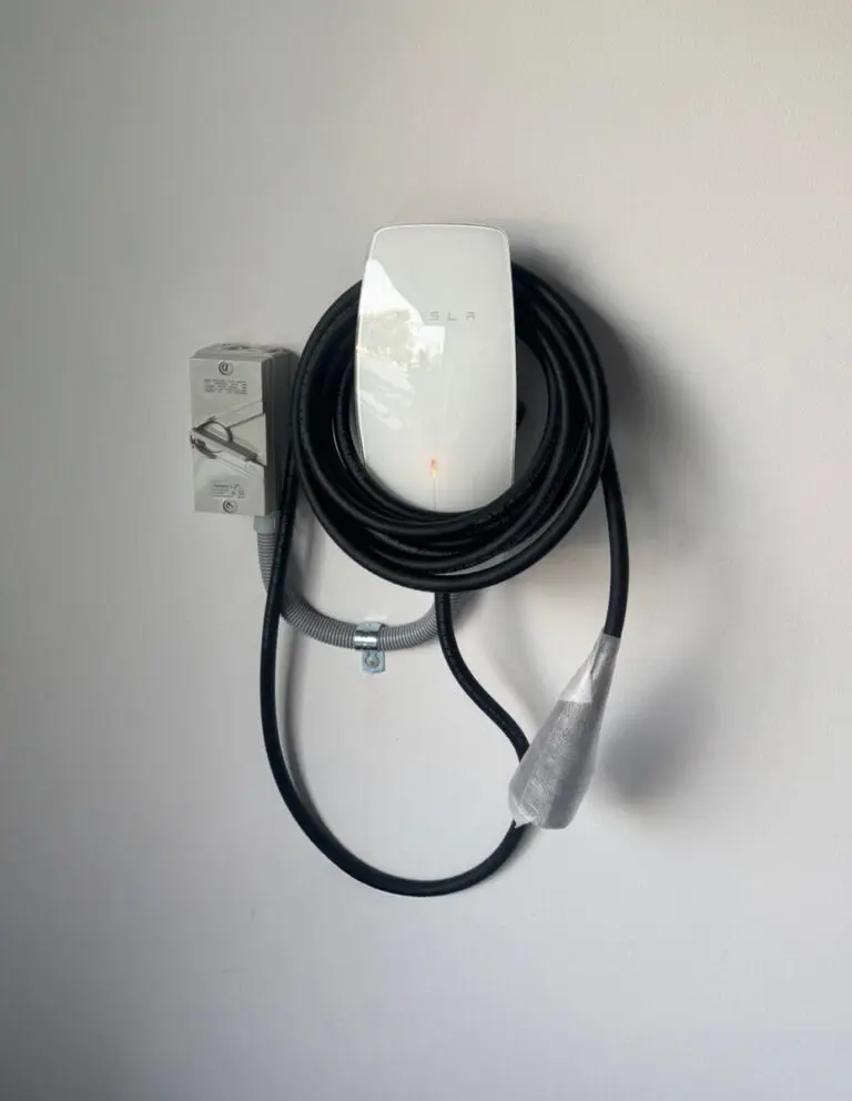Tesla wall connector with coiled cable mounted on a white wall for home EV charging