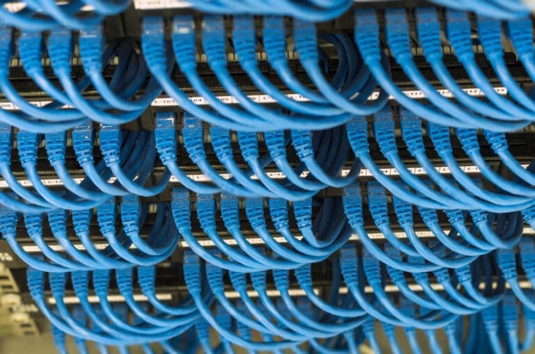 Detailed view of blue network cables connected to patch panels in a data centre