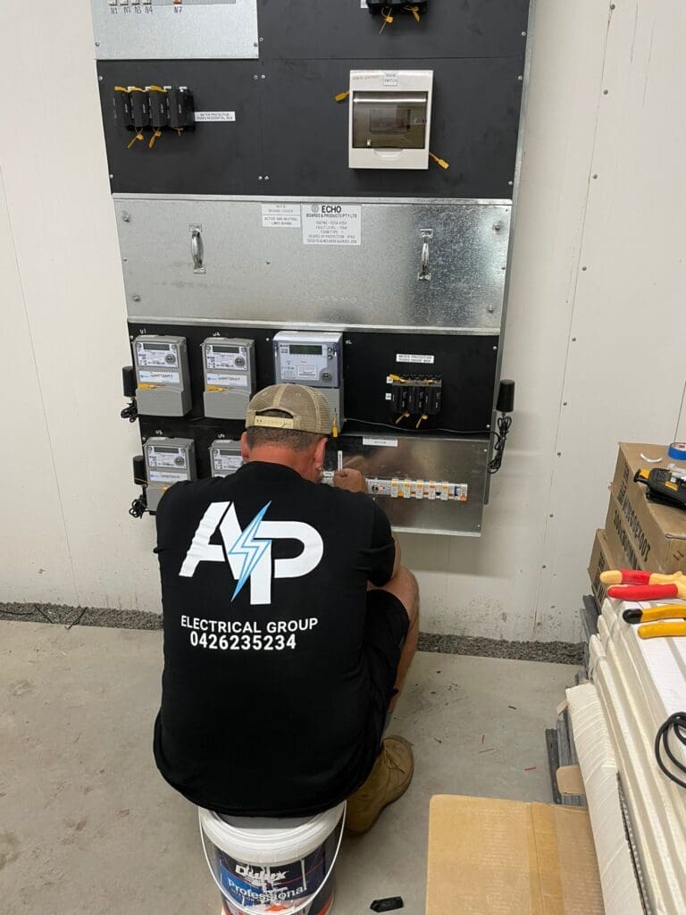 An AP Electrical Group electrician performing a switchboard upgrade installation in an industrial setting