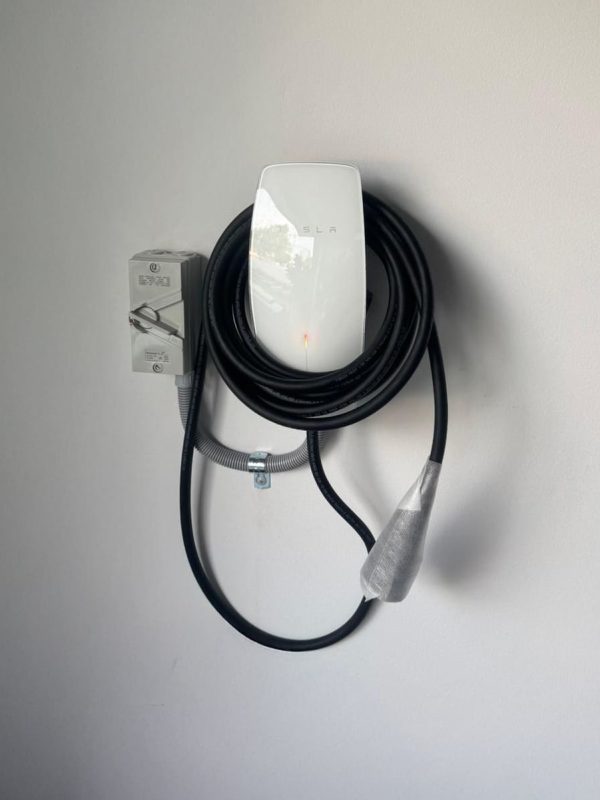 Tesla Wall Connector Installed Indoors Tesla wall connector with coiled cable mounted on a white wall for home EV charging